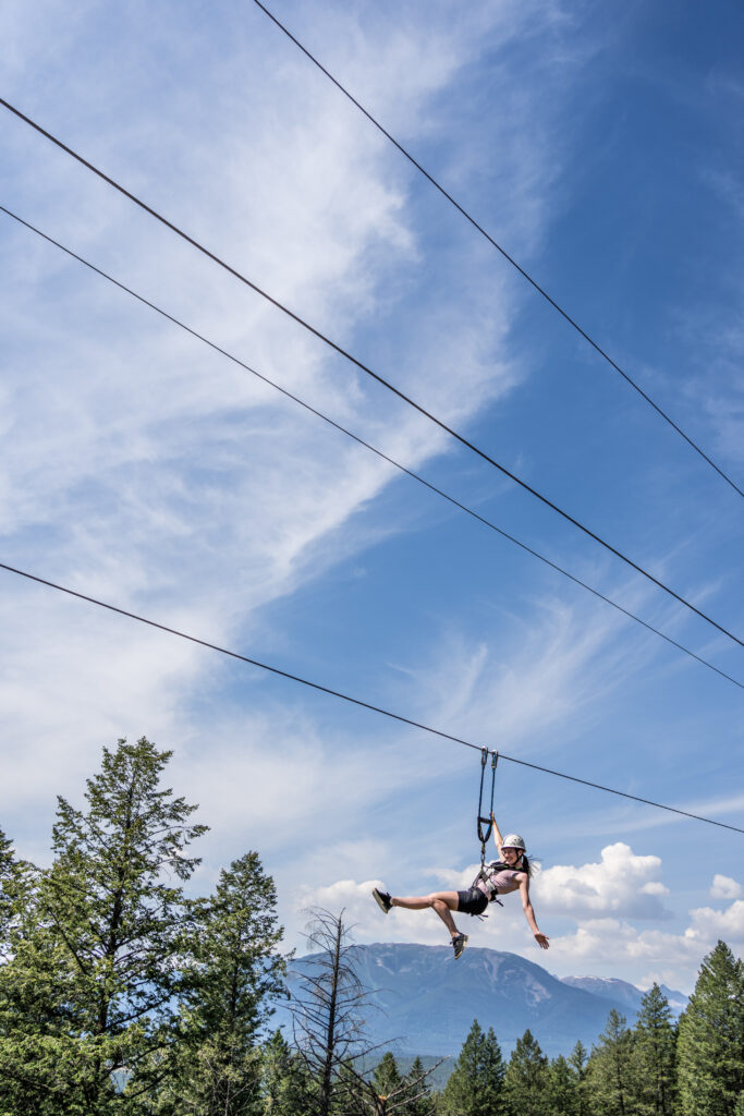 person crossing a zipline with a mountain backdrop